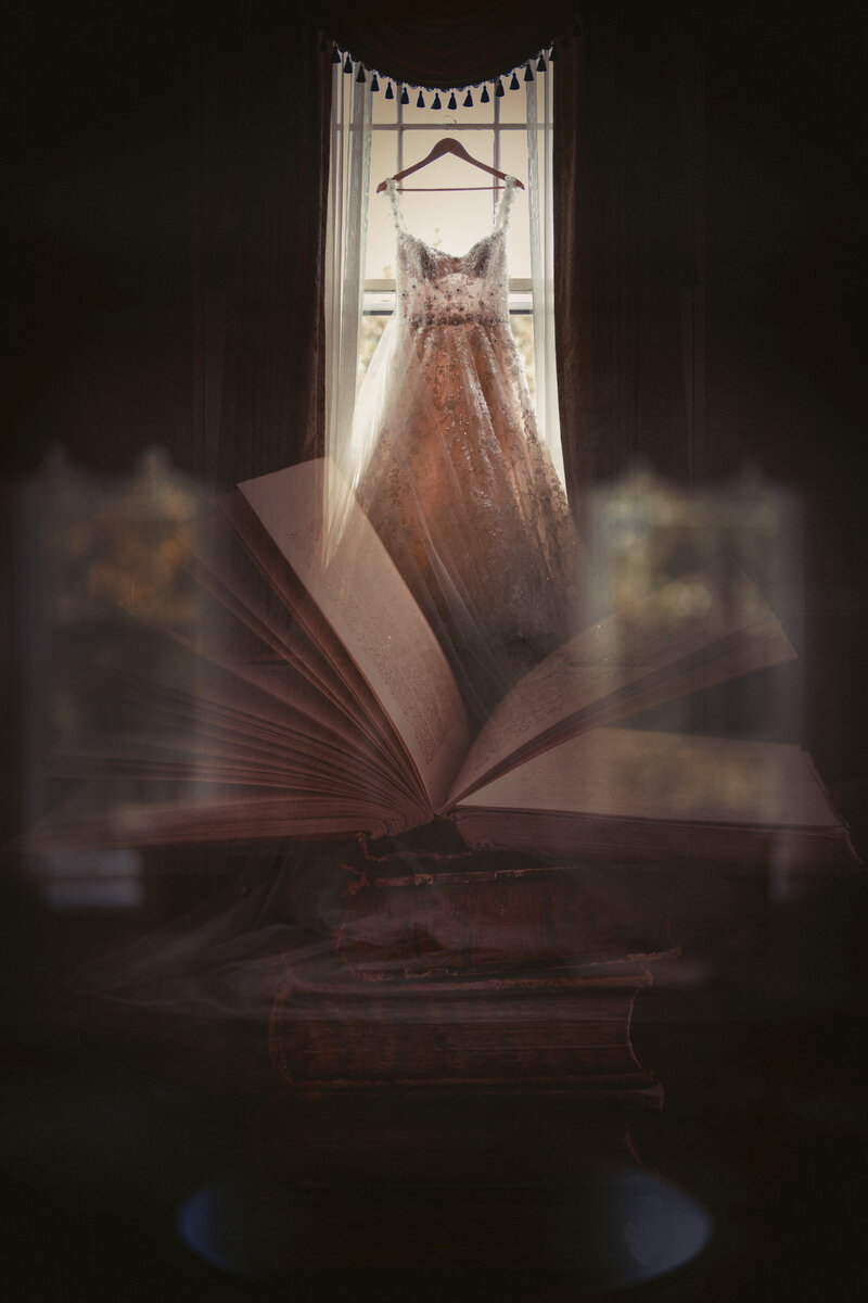 A book flipping in front of a dress handing from a window.