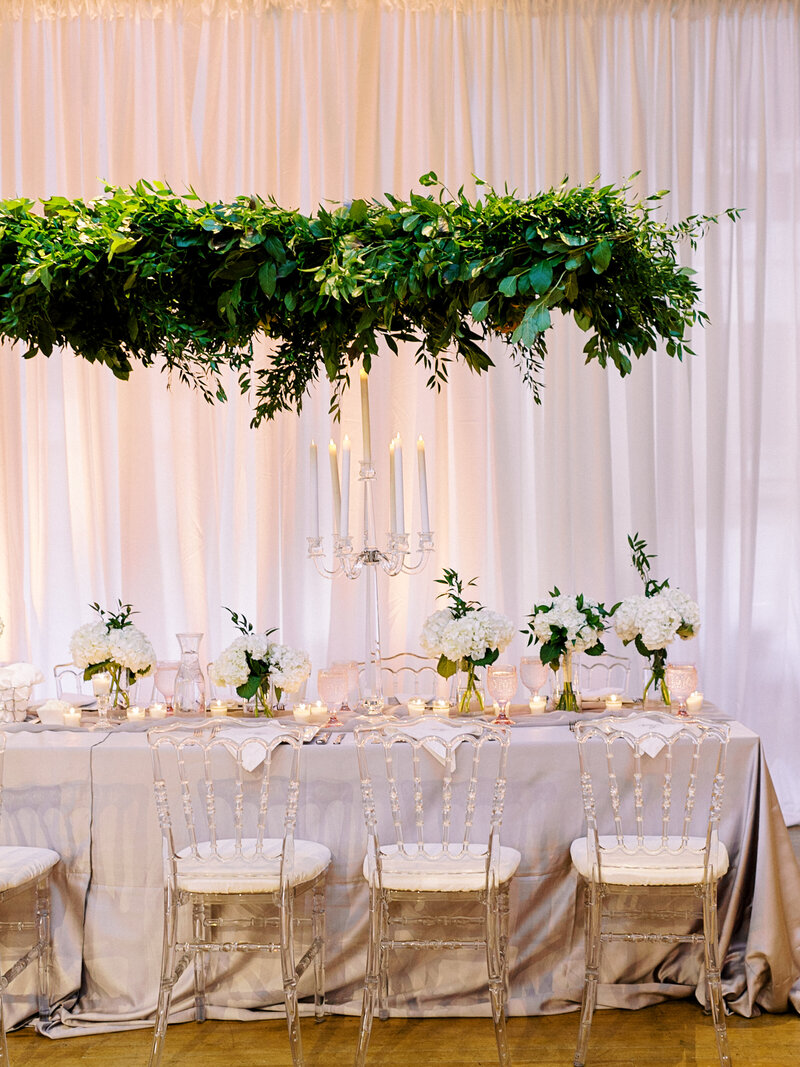 Romantic indoor wedding reception with lucite details and greenery
