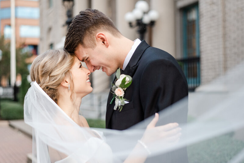 Wedding couple smiling forehead to forehead for photos.