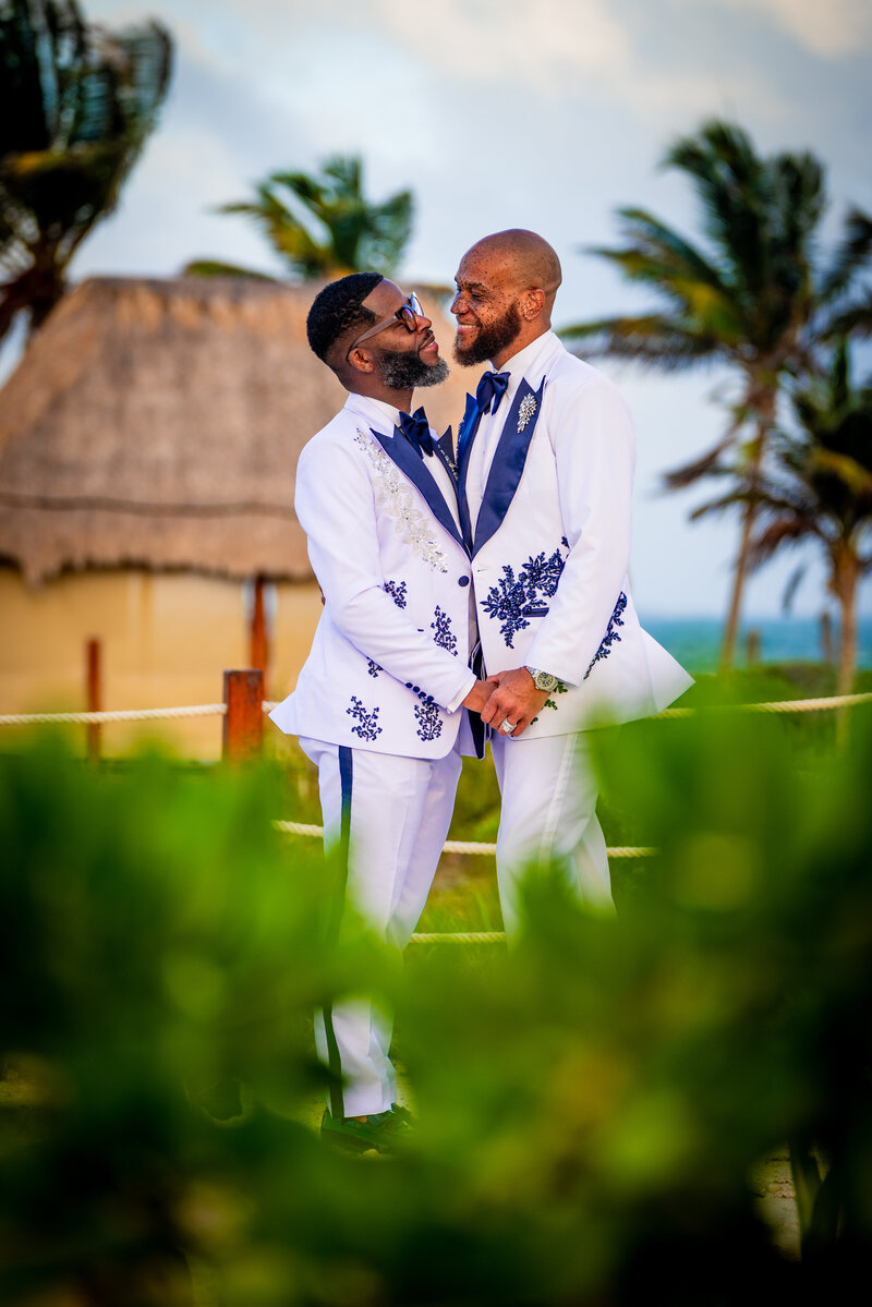 Gay couple facing each other smiling on their wedding day.