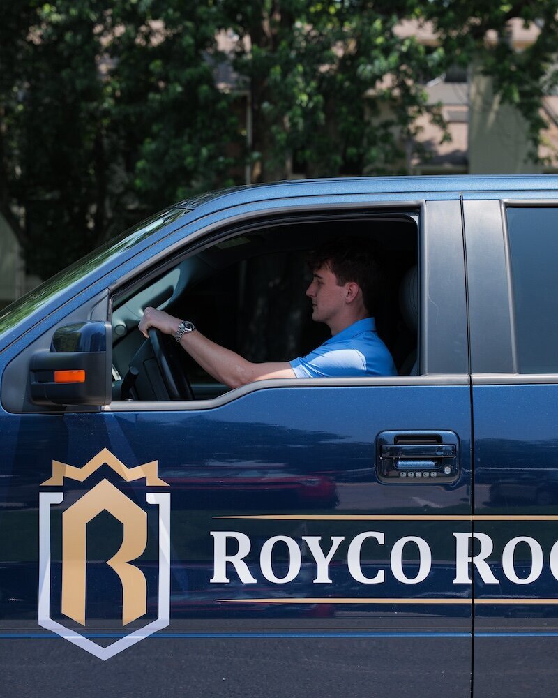 A member of the Royco Roofing team driving a work truck