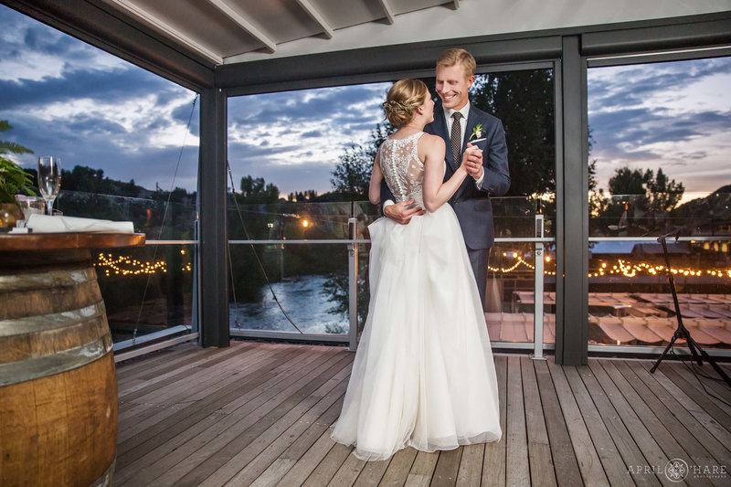 Bride and groom dance on outdoor covered balcony at their Aurum Food & Wine wedding reception in Steamboat Springs