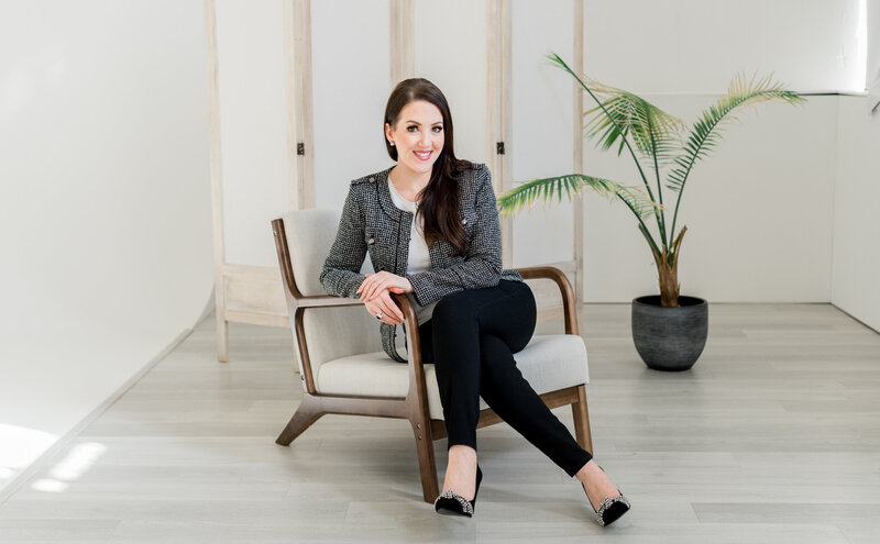 Ashley Turner, owner of Refresh Aesthetics, wearing a blazer and sitting in a chair in her office