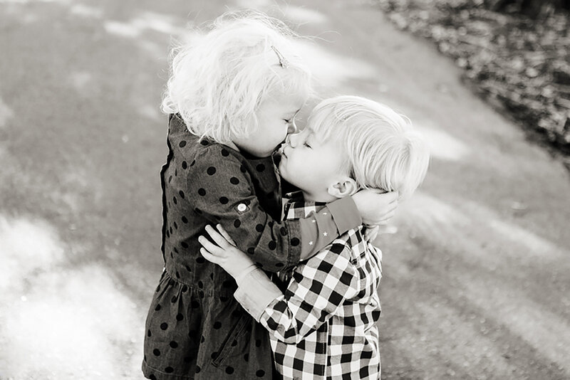 Black & white portrait of toddler siblings kissing  during their children's portrait session