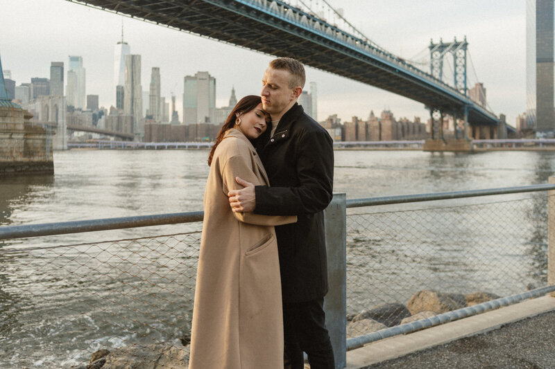Couple taking photos under the Brooklyn Bridge in DUMBO, Brooklyn.
