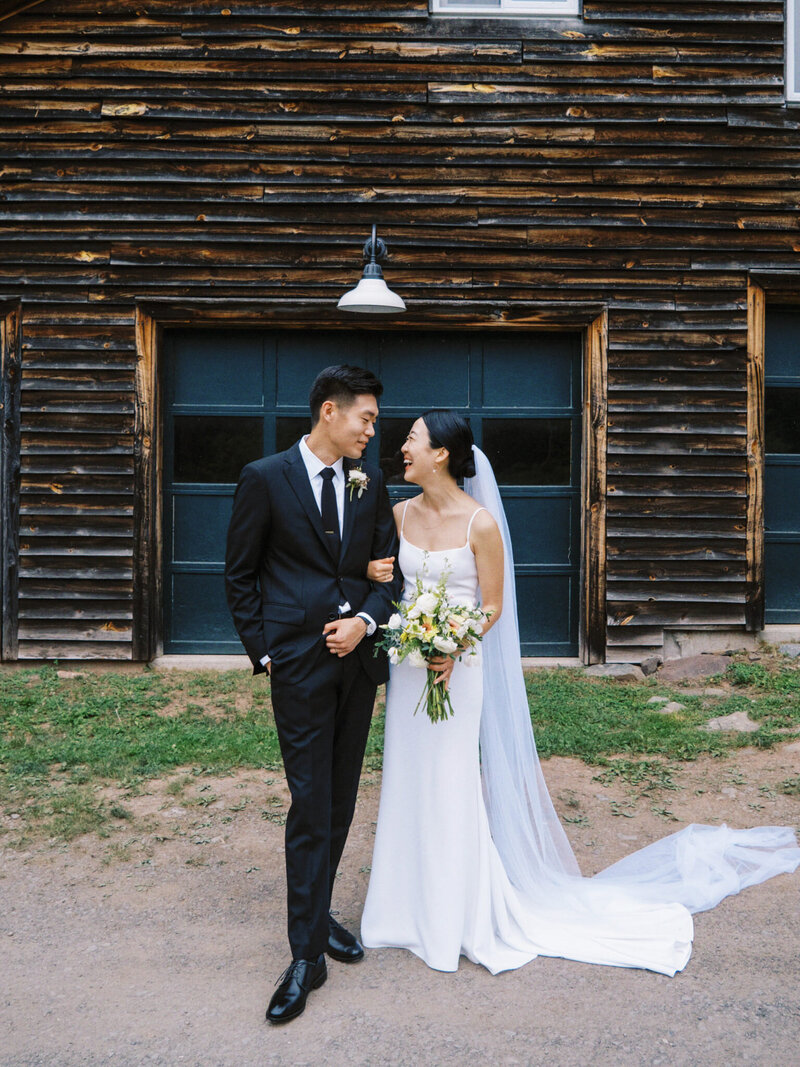 smiling bride and groom in front of rustic venue