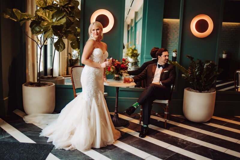 A bride and groom posed in a green room with white and black striped floors.