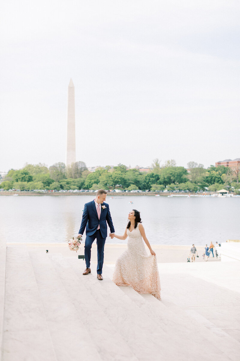 Bride and groom walk up marble stairs by the Washington Monument.