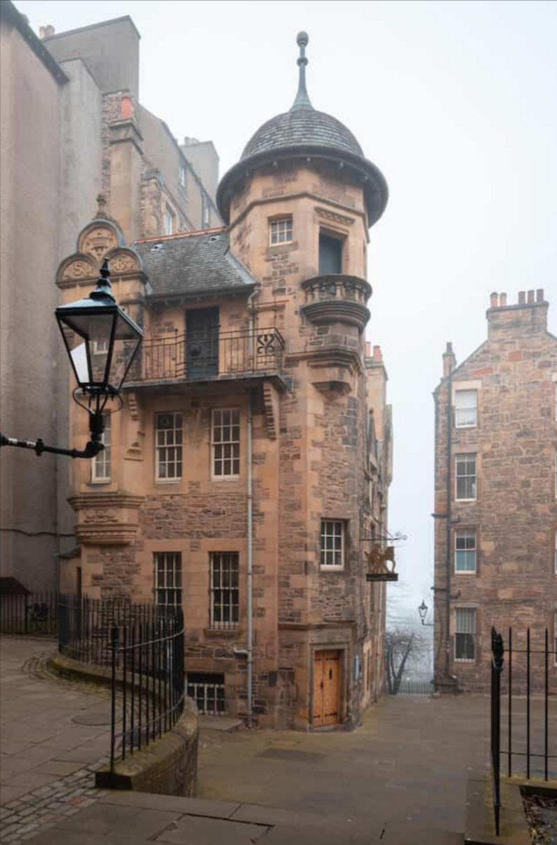 A historic stone building with a turret on a misty street, flanked by old lampposts and iron railings—captured perfectly by an Ouray Colorado elopement photographer.