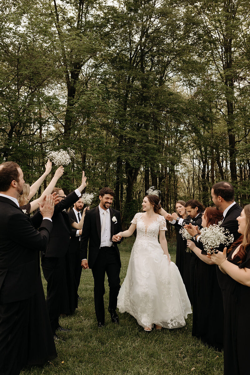 Couple holding hands walking through bridal party