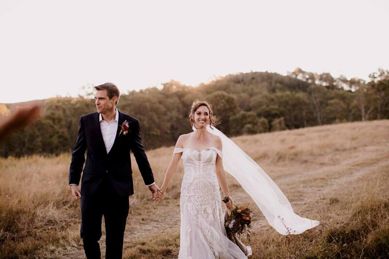 Wedding couple holding hands while walking at the farm
