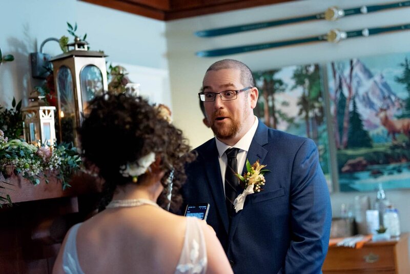 a groom makes a surprised expression as the bride reads her wedding vows