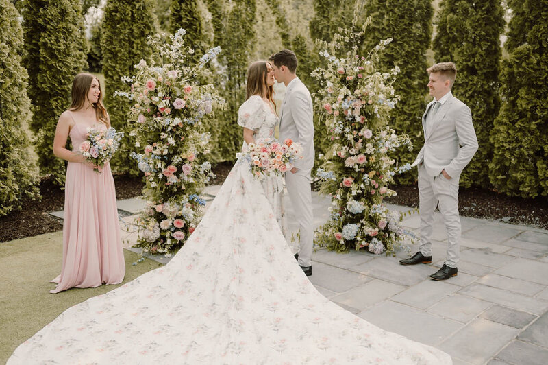 Whimsical backyard wedding attire for bride and groom with the bride wearing a floral wedding dress while holding a paper umbrella