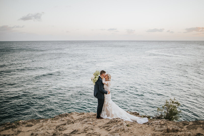 couple kissing cliffside on hawaii beach