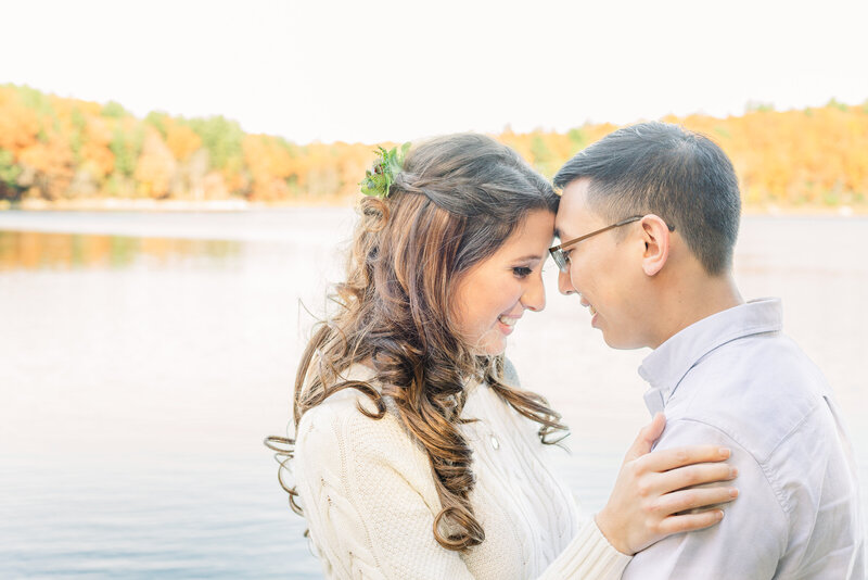 Celebrate love with an enchanting autumn engagement session by Lorie-Lyn Photography. This tender photograph captures a couple's intimate moment amidst the beauty of Massachusetts' fall foliage. Lorie-Lyn's expert use of natural light and her ability to create a comfortable and relaxed atmosphere shine through, making for truly genuine and joyful engagement memories.