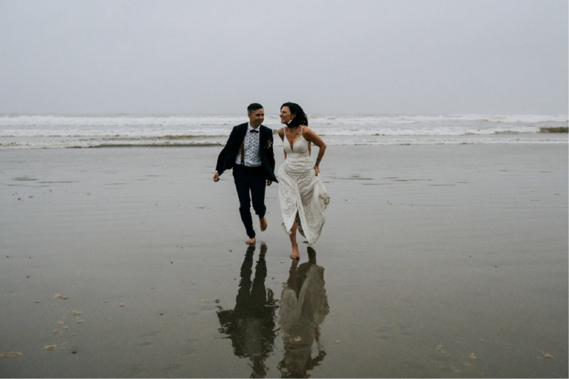 wedding couple running barefoot on the beach in Tofino