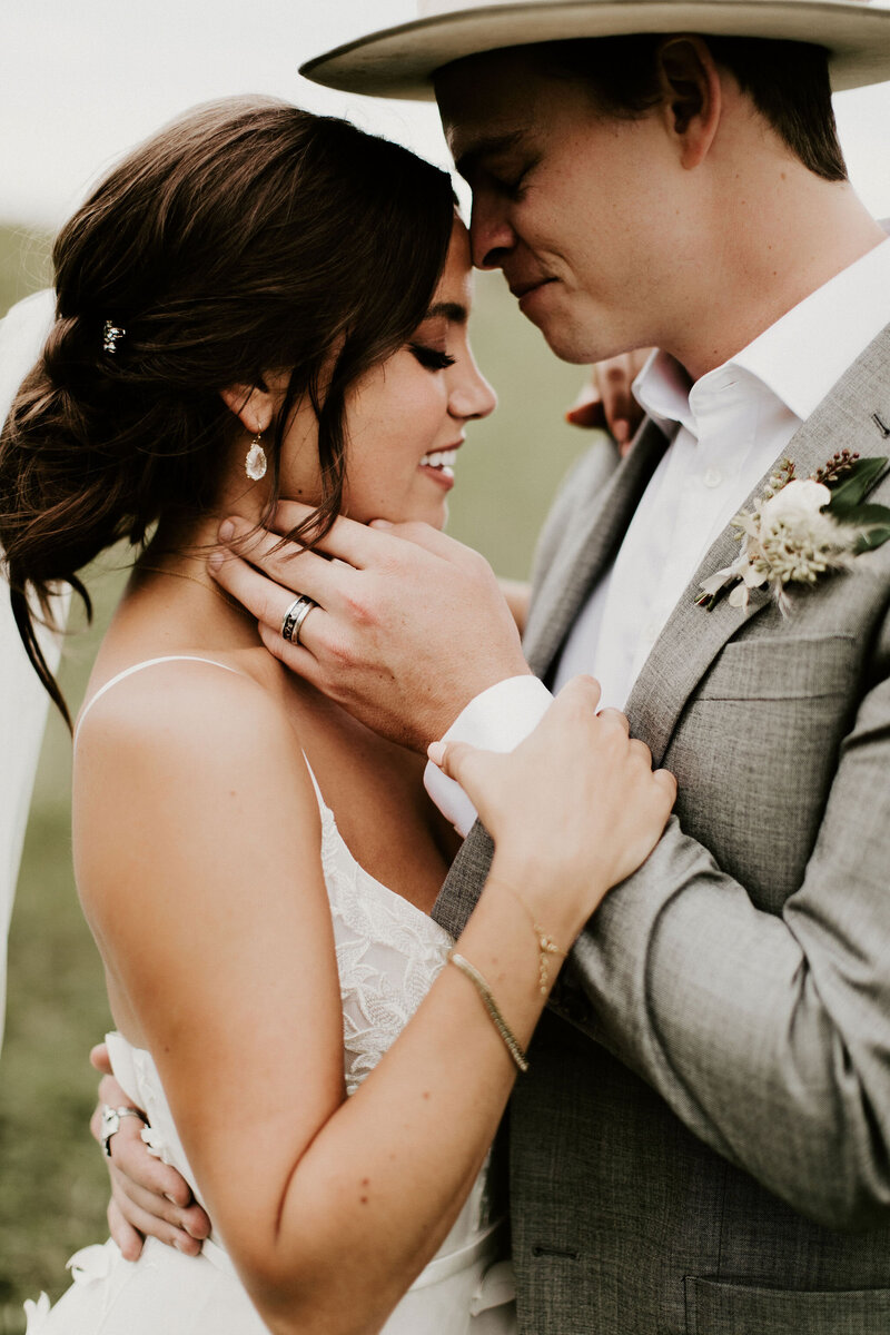 Bride and groom leaning in close to each other and smiling with their eyes closed
