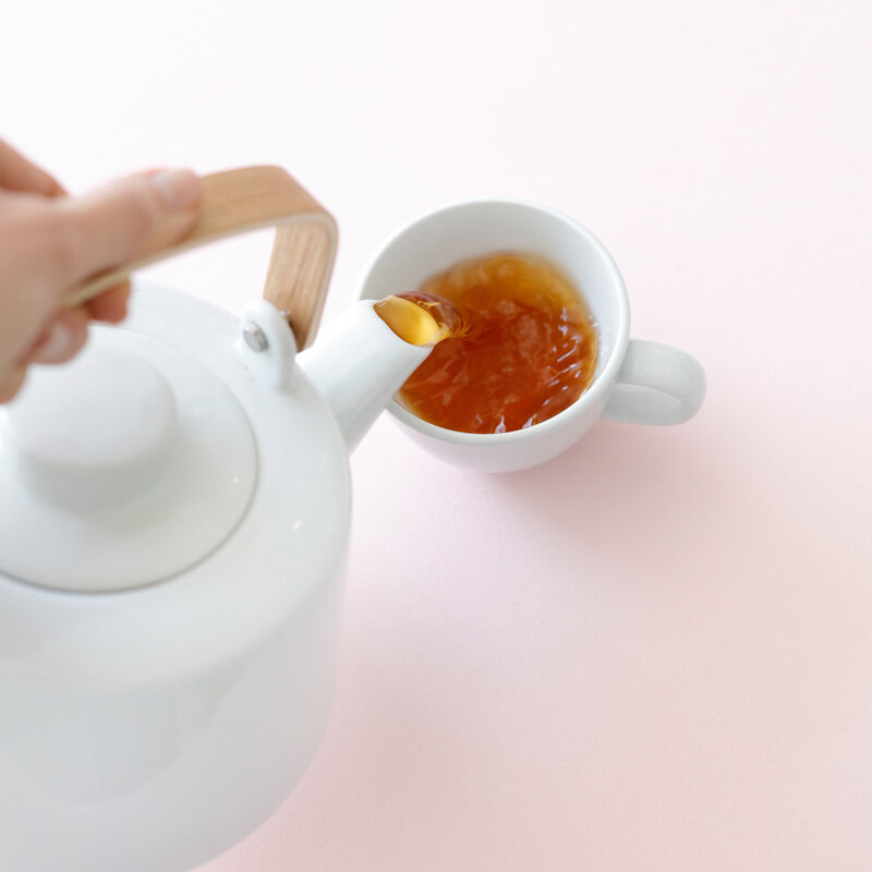 White tea pot pouring into a white mug