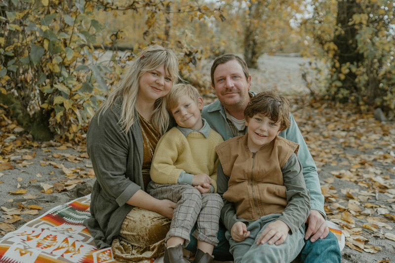 family sitting on sand with fall colors
