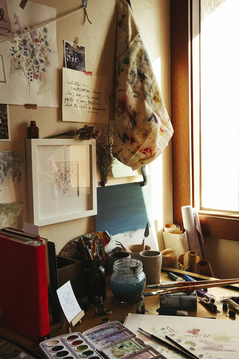 desk with artwork and art supplies