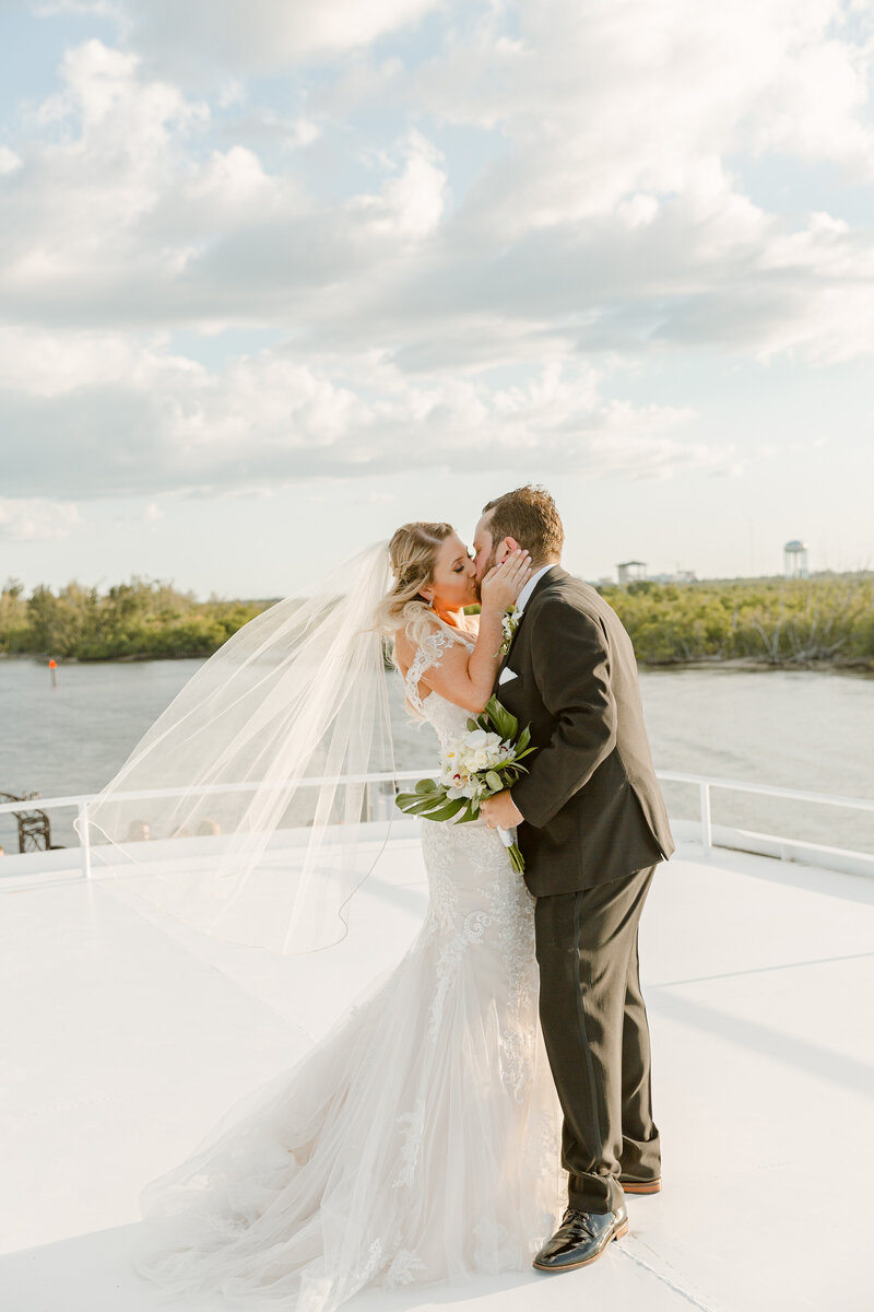 Bride and groom kiss on the deck of a yacht on their wedding day in Florida