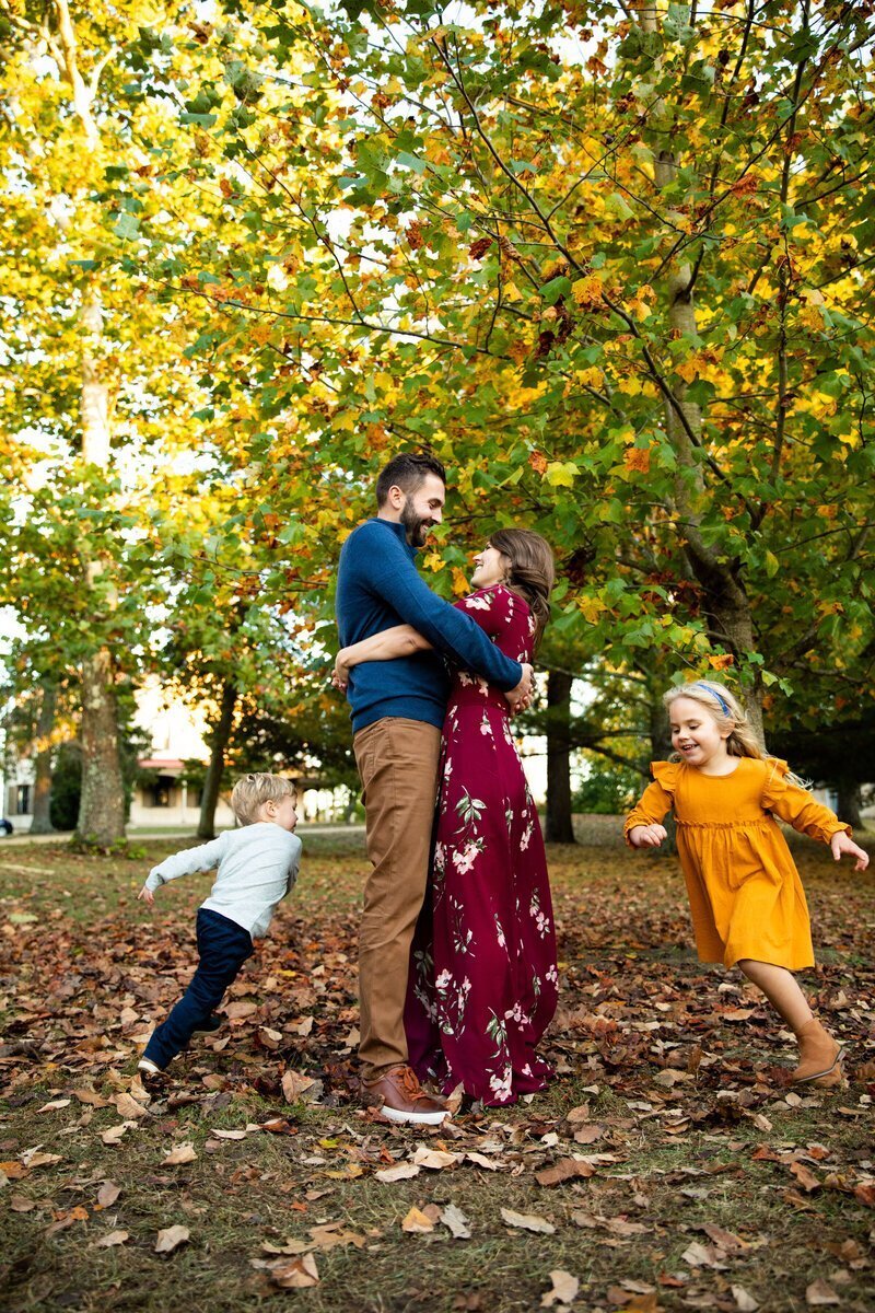 Parents embracing and children running around taken by family photographers new jersey
