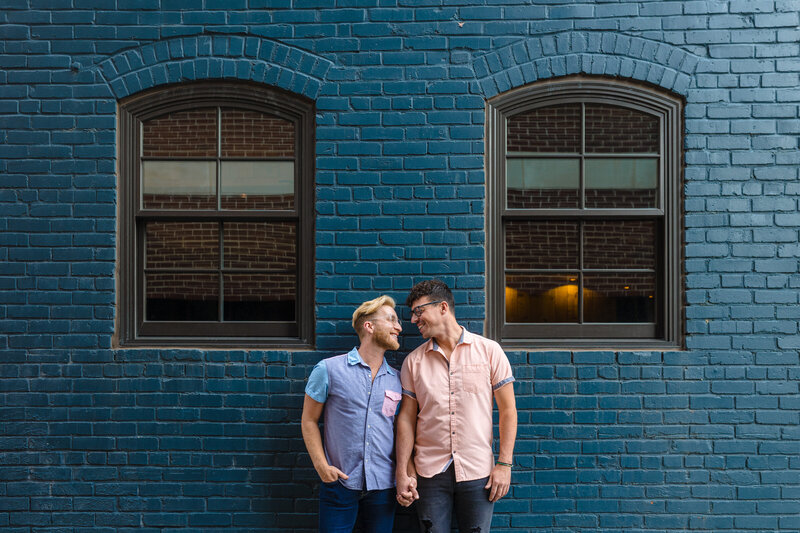 Gay couple posing in front of blue wall