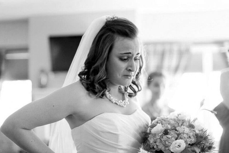 A bride crying as she holds a bouquet of flowers.