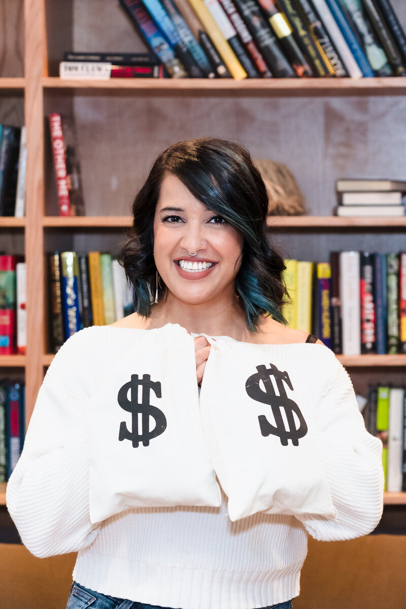 brand photo of a business coach holding two bags with money sign to represent her business