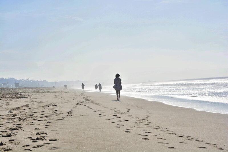 Ein sonniger Tag am Meer, an dem vereinzelt Menschen den Strand entlang laufen.