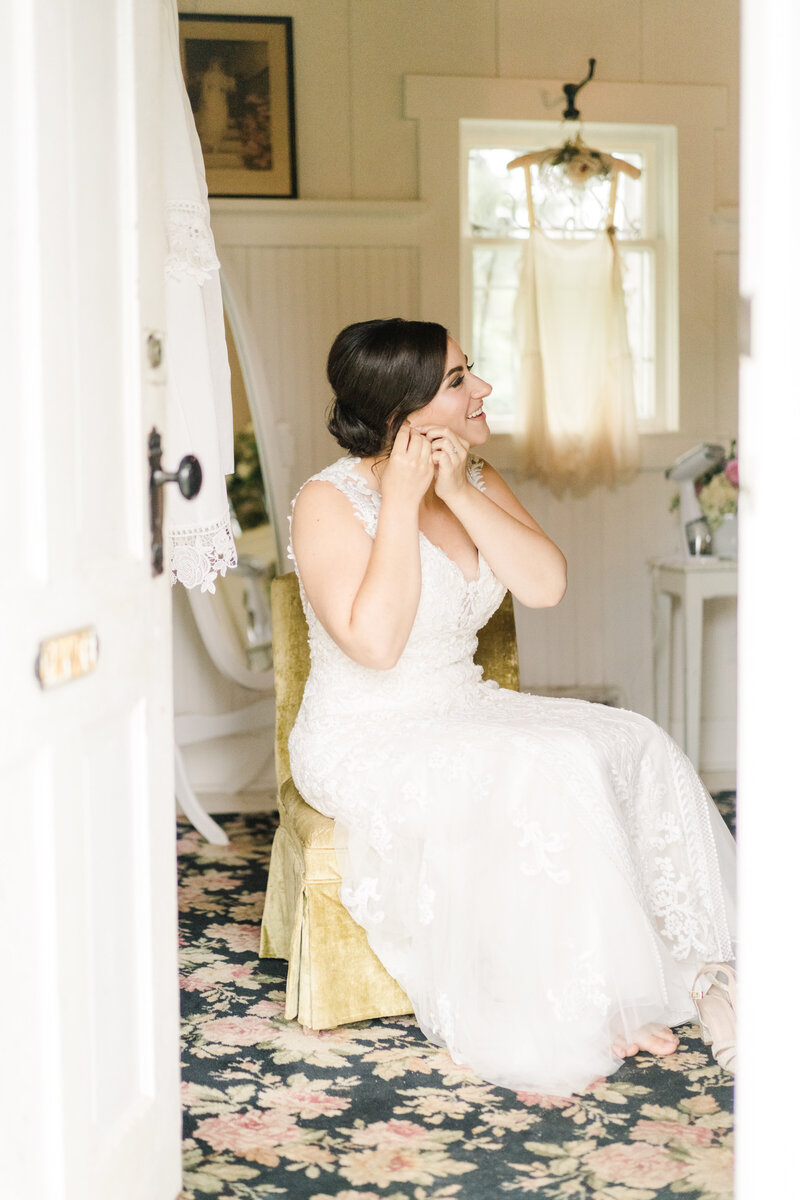 bride sitting down and putting earrings in