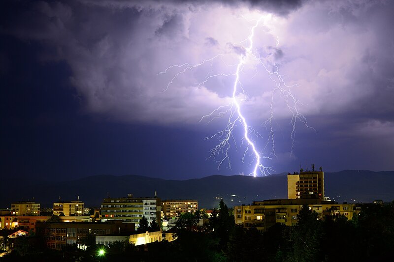 lightning bolt striking the earth behind a city