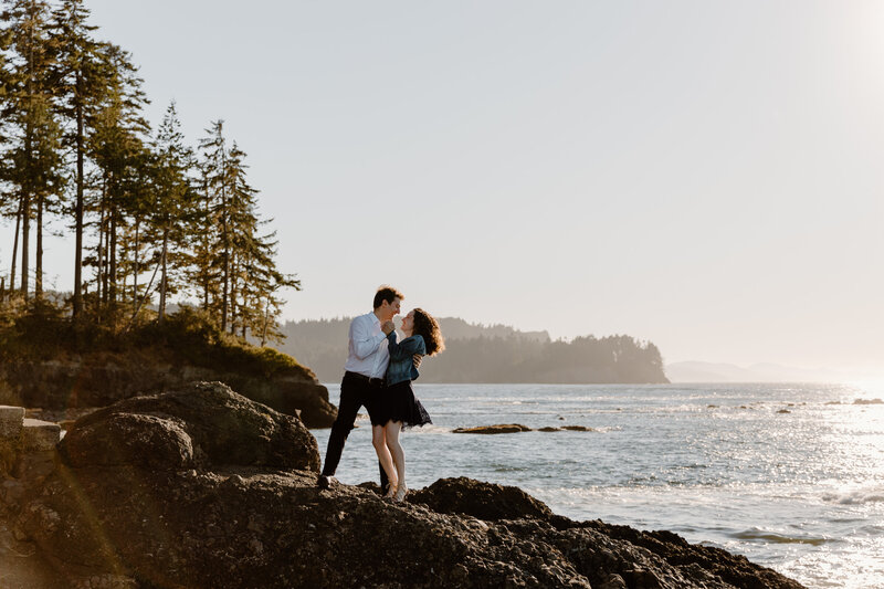 Couple dances on a rocky ledge above the sea at Washington engagement session captured Washington elopement photographer