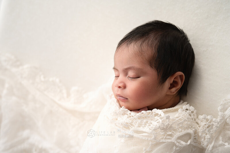 baby girl profile on white backdrop and lace blanket