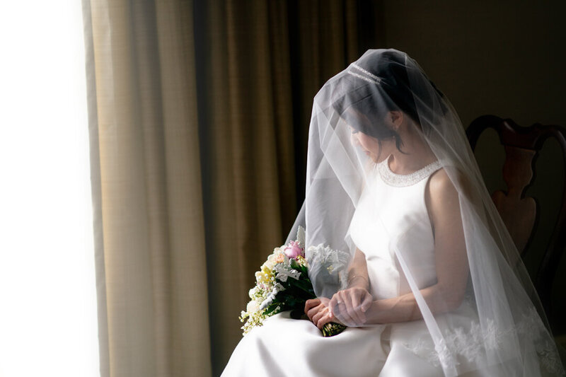 View of the bride from the side, with her veil on and a bouquet in her hands