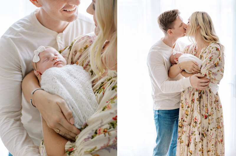 New parents kiss each other while holding their newborn baby girl.