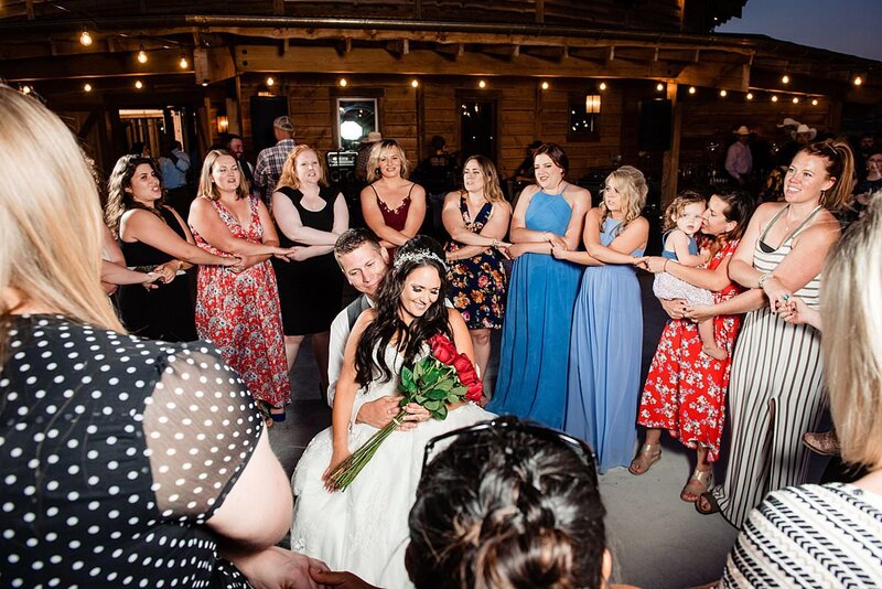 Alpha Omicron Pi bride sitting on her husbands lap with her sorority sisters serenading them at Headwaters Ranch