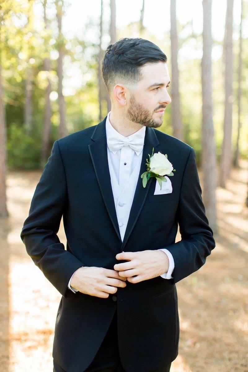 handsome dark haired groom in a black tuxedo with a white bowtie