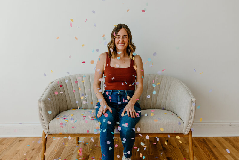 Bridget sitting on vintage couch with colorful confetti falling around her.