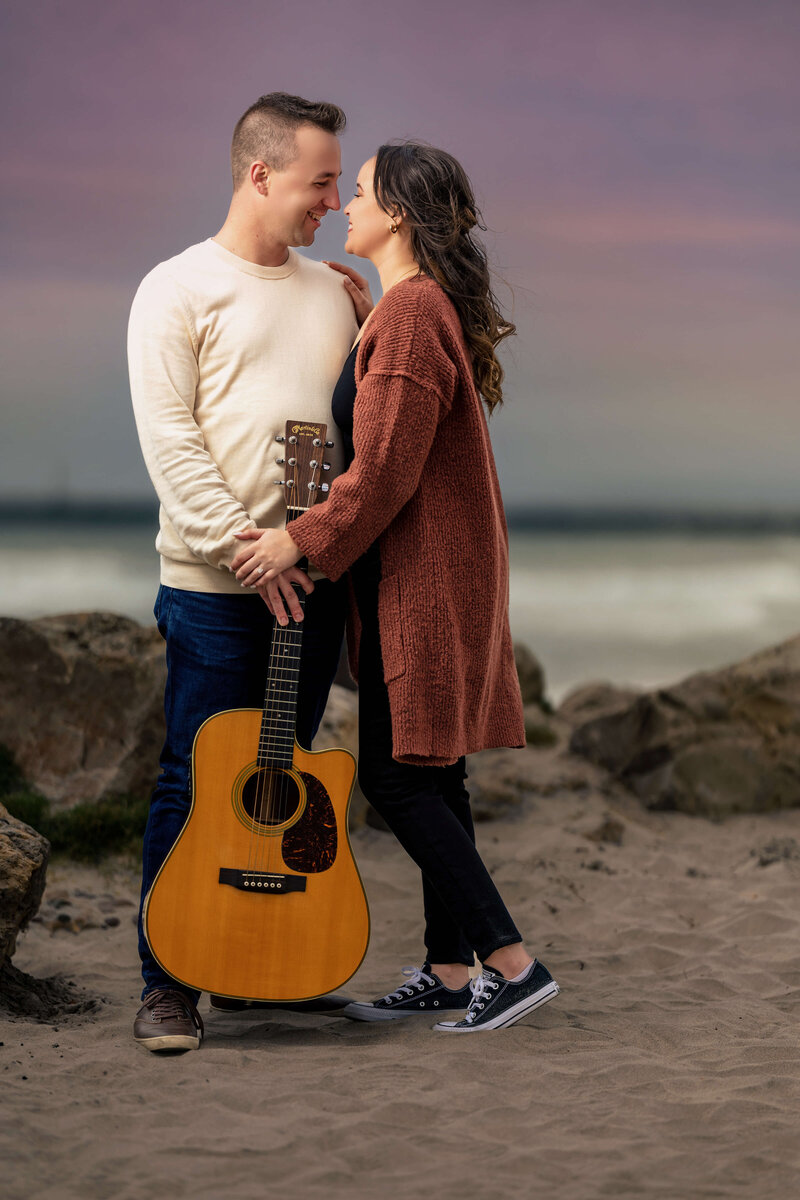 Couple portraits of Paul Michael Cooper, San Diego wedding photographer and his partner on the beach holding a guitar