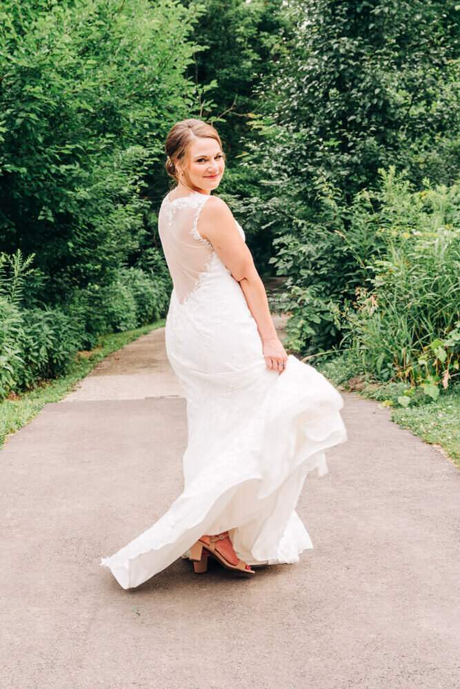 A bride dances and shows off her dress in a nature covered path in the summer in northern Michigan.