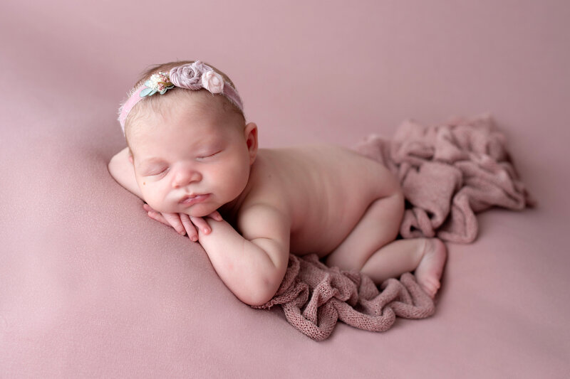Baby girl sleeping with head in hands during newborn photo session.