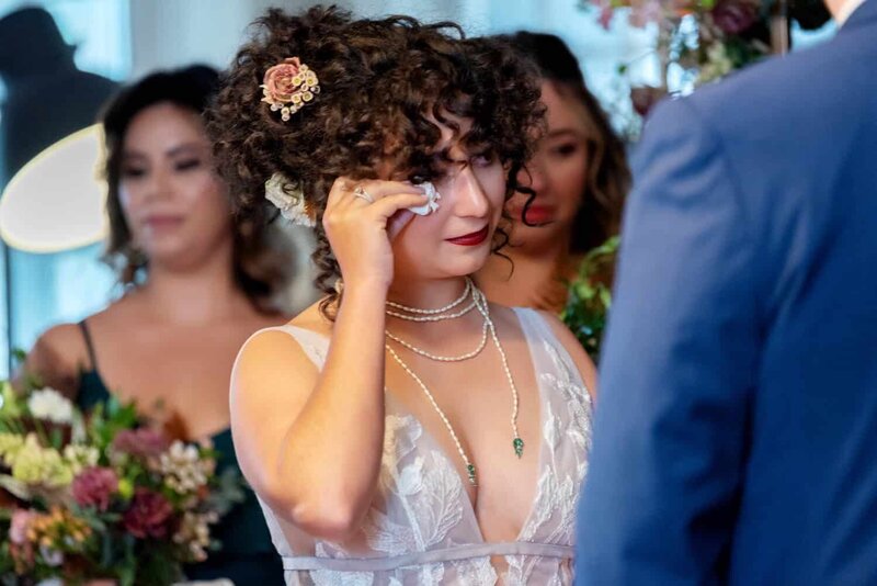 a bride wipes a tear away from her face during a wedding ceremony