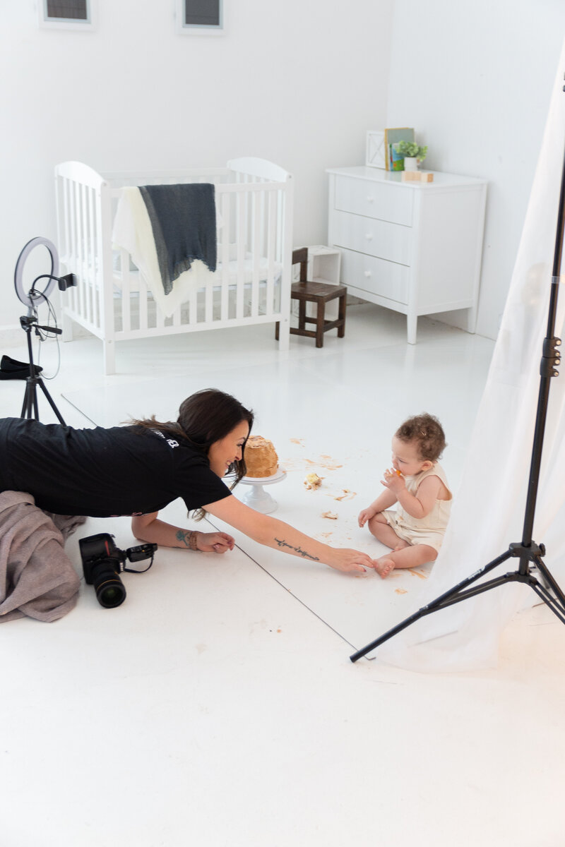 A childrens photographer takes a picture of a toddler boy in a studio