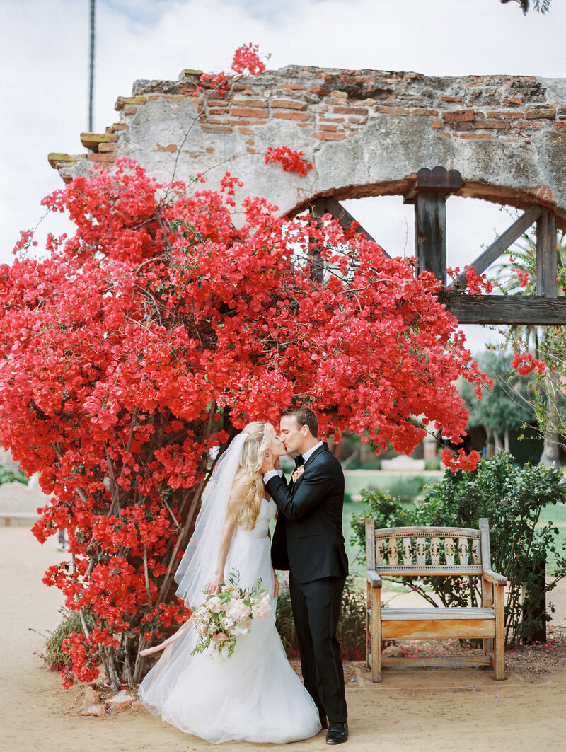 full bloom pink bougainvilla at the mission san juan capistrano with couple kissing in front