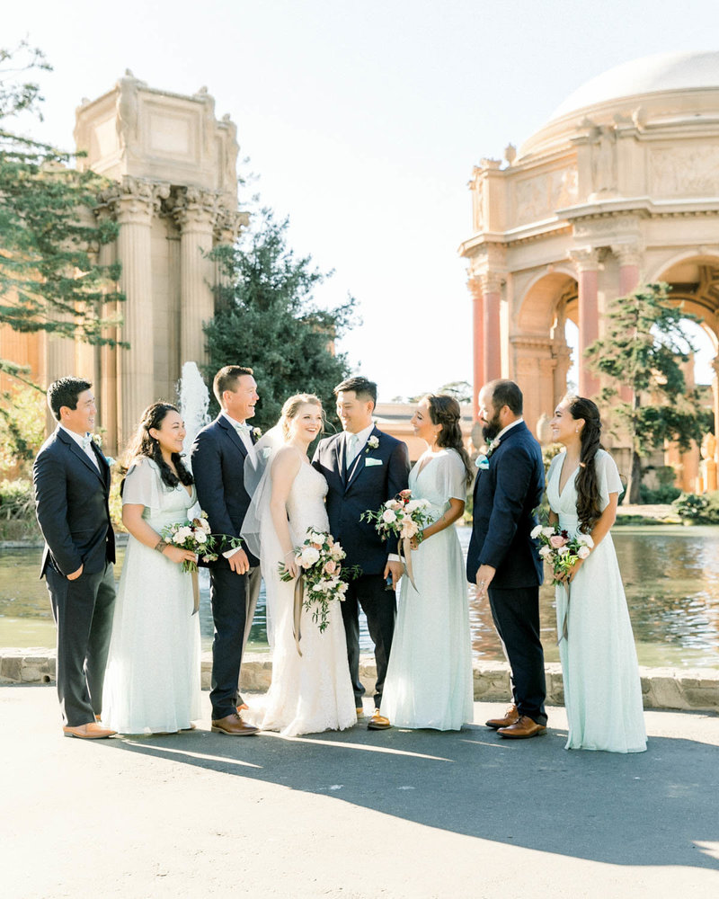 Candid of Bridal Party surrounding Bride +  Groom