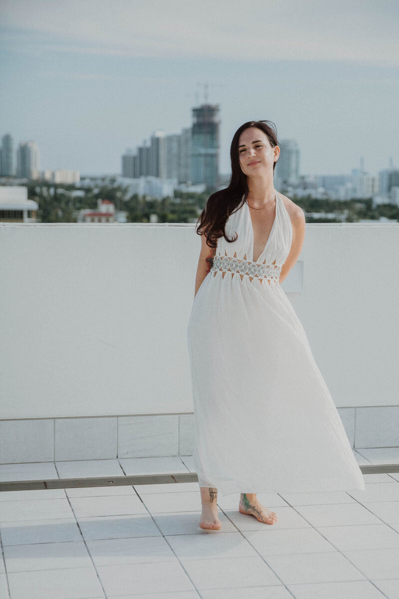 Ayurvedic skin specialist, Jen, wearing a white dress with the city skyline in the background