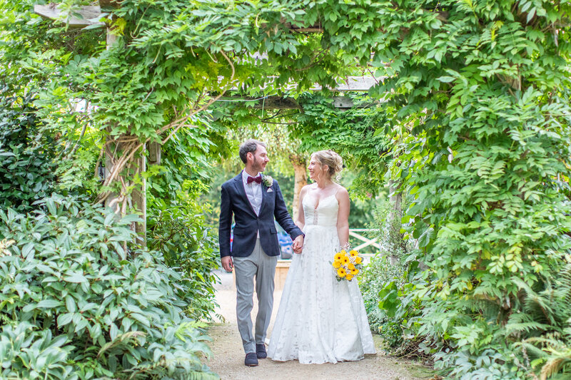 Bride and Groom walking through garden path