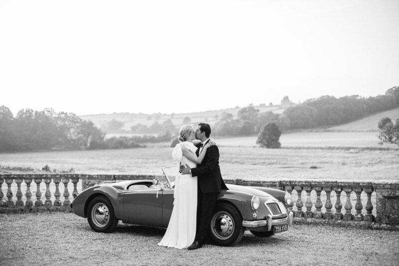 Bride and groom posing with antique car