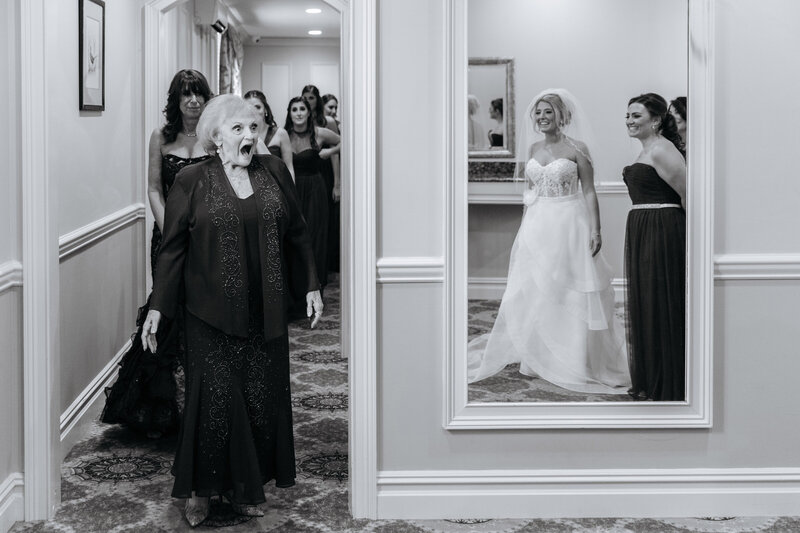 A grandmother with a shocked look on her face as she sees a bride for the first time.